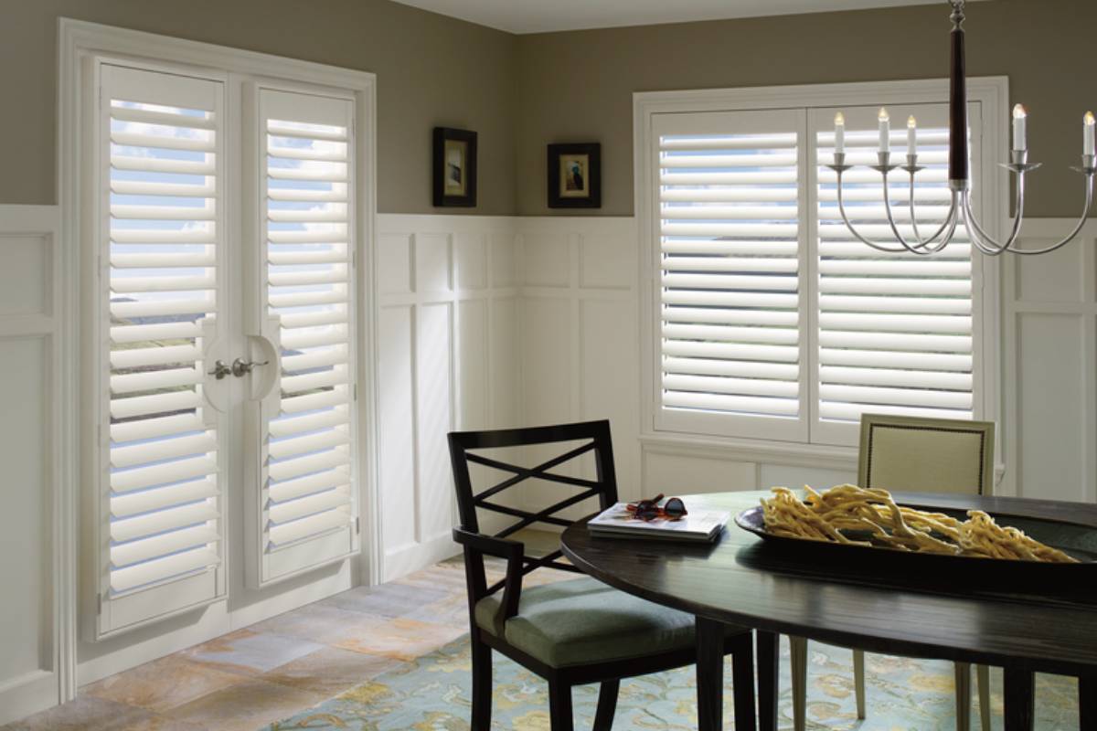 A dining room with two sets of Hunter Douglas Palm Beach™ PolySatin™ Vinyl Shutters